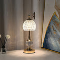 Elegant table lamp with a metallic base and decorative glass shade, perfect for bedroom or living room interiors.