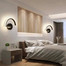 Black arc LED wall sconces on a wooden panel wall in a modern bedroom