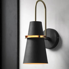 Black and gold industrial wall light mounted on a white wall, featuring a sleek modern design with a gold accent ring.