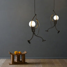 Stylish black metal pendant lights in the shape of a little man, hanging against a dark gray background, creating a modern industrial look