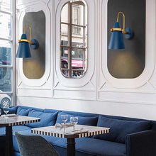 Blue and gold industrial wall lights enhancing the ambiance of a chic café with large windows and seating.