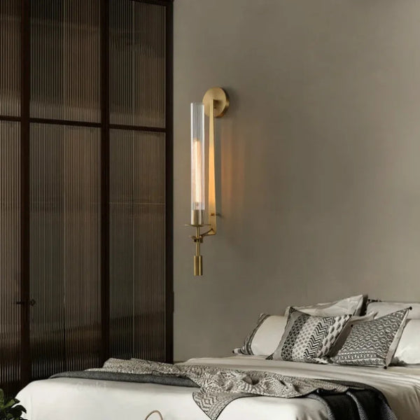 Brass wall lamp elegantly installed beside a bed in a contemporary bedroom interior.