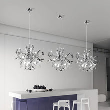 Three contemporary chrome ceiling lamps illuminating a modern kitchen bar with a minimalist touch.