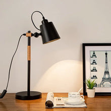 The LOFT1 Desk Lamp in black, placed on a wooden desk with minimalist decor.