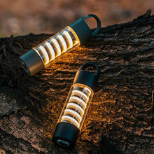 Two LumiTrail camping lights in flashlight mode, placed on a tree trunk at night.