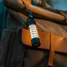 A LumiTrail camping light clipped to a backpack, showing its portable and travel-friendly design.