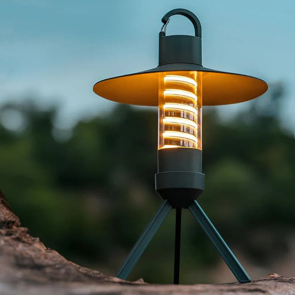 A stylish outdoor camping lantern glowing in warm light on a wooden surface.