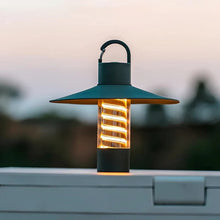 A LumiTrail camping lantern placed on a table, illuminating the outdoor setting.