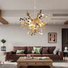 Luxury gold chandelier hanging in a sophisticated living room, casting a warm glow over a stylish seating area with modern decor.