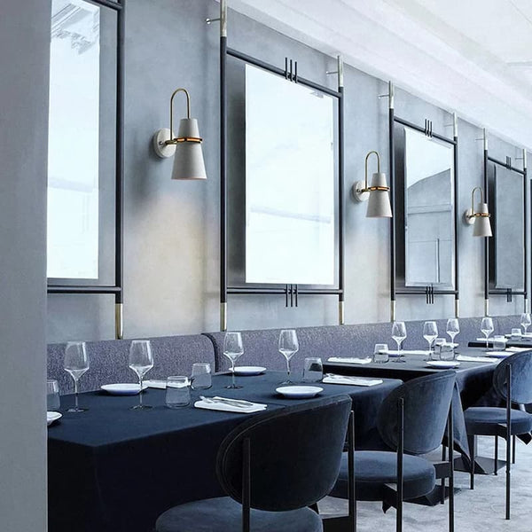 White and gold modern wall lights installed in a stylish restaurant interior with dining tables and mirrors.