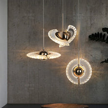 Three Ånd Lys pendant lamps in different orientations, emitting warm golden light against a modern concrete wall background.