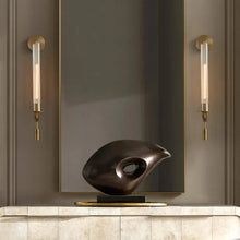 Pair of brass wall sconces placed on both sides of a mirror, enhancing the modern decor.