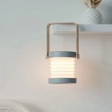 TrailOrb 4-in-1 Folding Lamp hanging from a shelf, illuminating the wall with soft, ambient lighting.