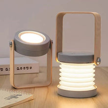 TrailOrb 4-in-1 Folding Lamp in spotlight and lantern mode with a wooden handle, displayed on a wooden desk.