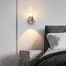 Wall-mounted LED sconce on the left side of a bed, casting warm light in a minimalist bedroom.