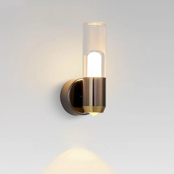 Close-up of a modern wall light with cylindrical acrylic shade and brushed black-and-gold metal body.