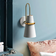 White and gold wall lamp installed in a bedroom interior with soft pastel blue walls and elegant furnishings.